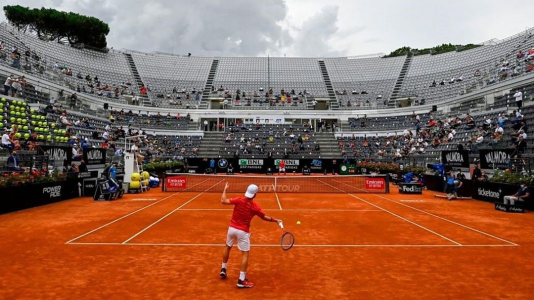 Jugador de tenis en una cancha de arcilla a punto de golpear la pelota
